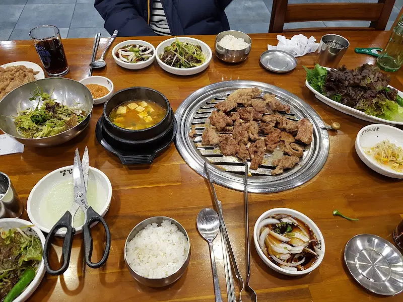 테이블 위에 놓인 숯불, 초벌된 갈비, 밑반찬들. 푸짐한 한 상 차림이 먹음직스럽다.