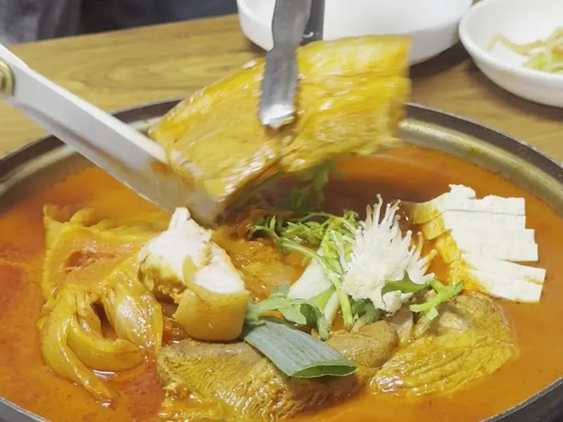 김치와 고기를 집게로 들어올리는 모습