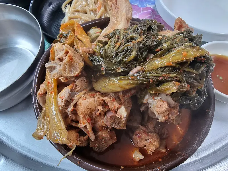 쟁반 위에 뼈해장국과 다양한 반찬이 함께 놓여 있는 모습