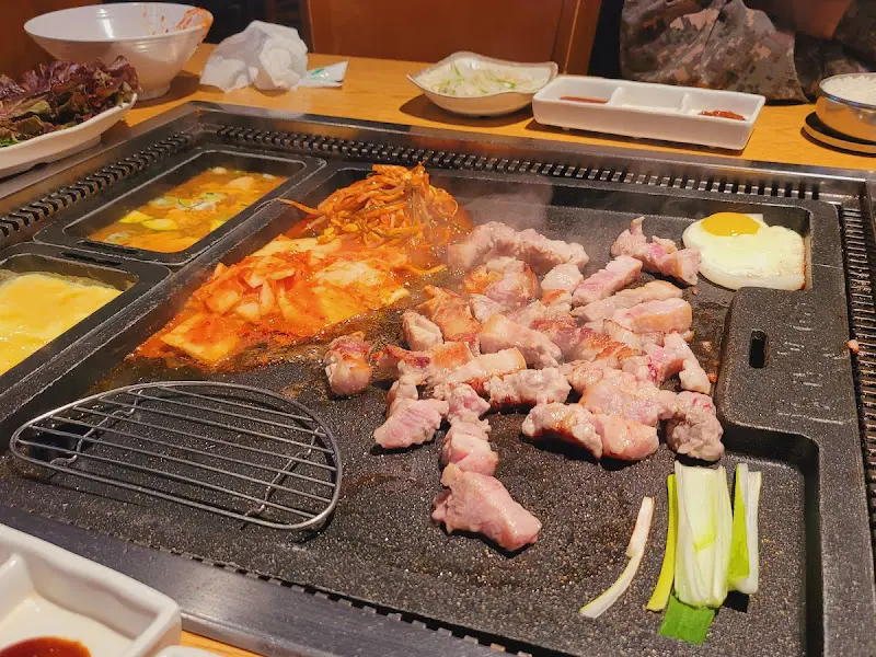 철판 위에서 삼겹살과 김치가 구워지고 있는 모습