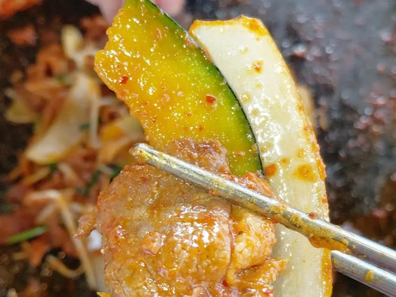 오리고기와 호박을 함께 젓가락으로 집어 올린 클로즈업 샷