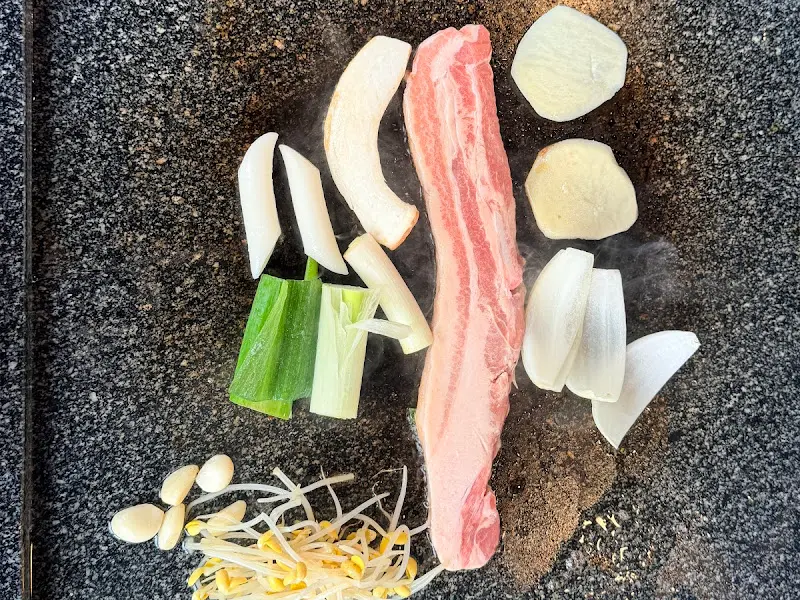 돌판 위에 올려진 삼겹살과 채소