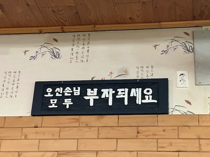 벽에 걸린 '오신손님 모두 부자되세요' 문구