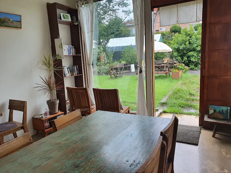 카페 내부에서 정원을 바라본 모습: 창밖으로 푸른 잔디밭과 테이블, 의자들이 보인다.