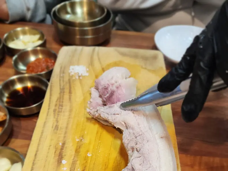 돔베고기가 놓인 나무 도마와 곁들임 찬들이 놓인 테이블