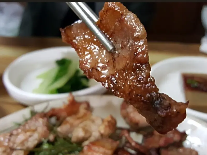 젓가락으로 집어 올린 숯불구이 한 점