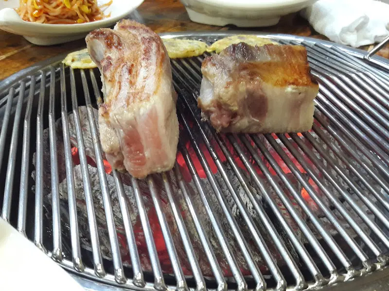 초벌된 통삼겹살이 숯불 위에 놓여 있는 모습