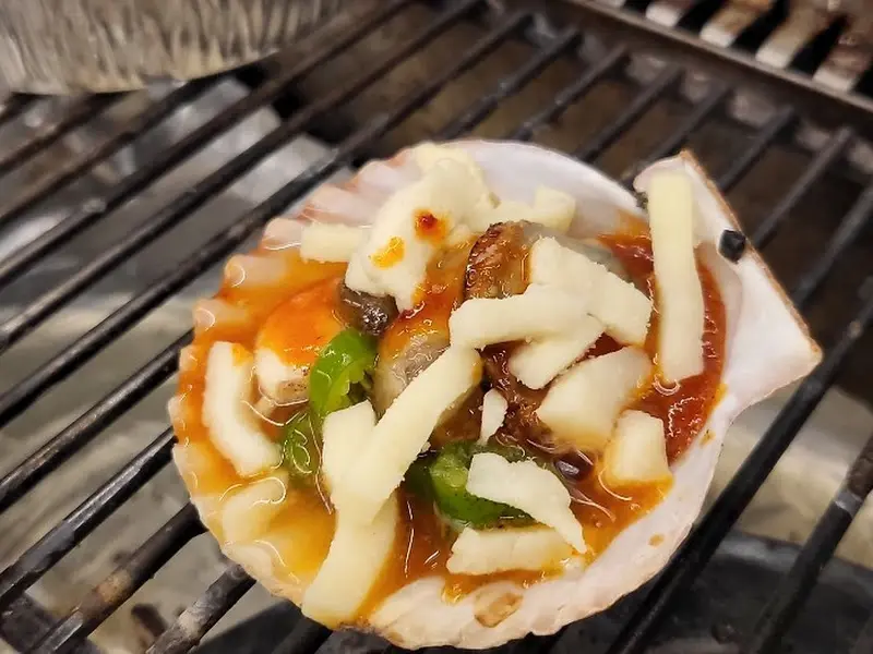 가리비에 치즈를 올려 구워 먹는 모습