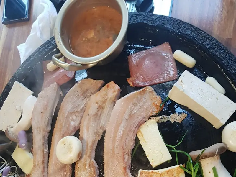 솥뚜껑 위의 삼겹살과 다양한 재료들