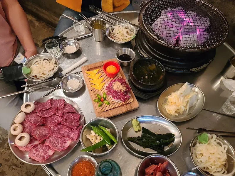 다채로운 곁들임 찬과 숯불이 세팅된 테이블 전경