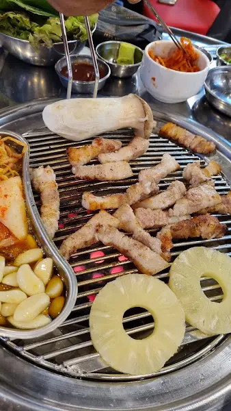 불판 위 삼겹살과 김치, 마늘