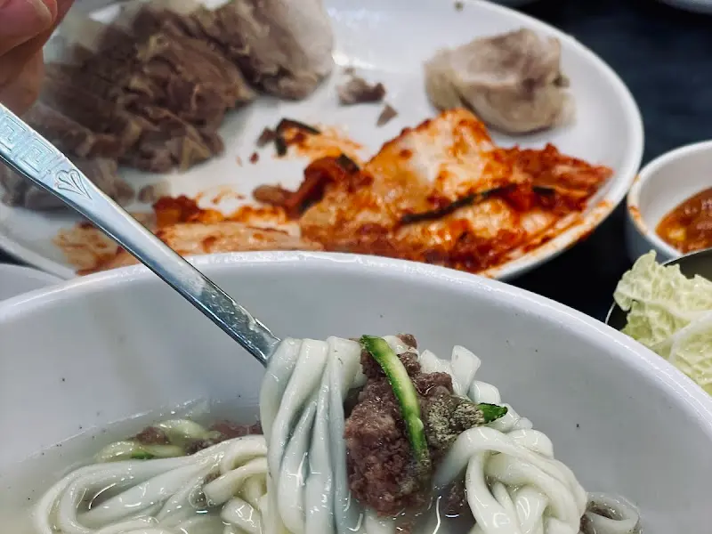수저 위에 가지런히 올려진 칼국수 면발과 고명