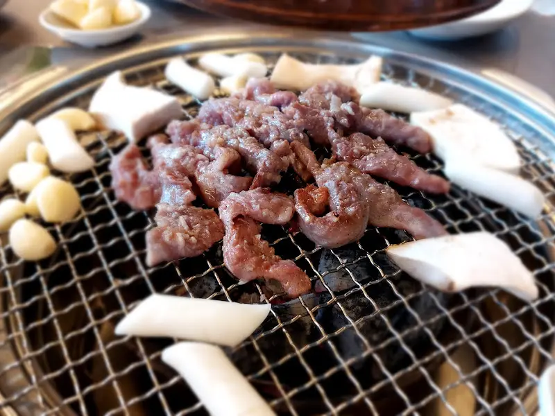 갈매기살, 떡, 마늘이 함께 구워지는 모습