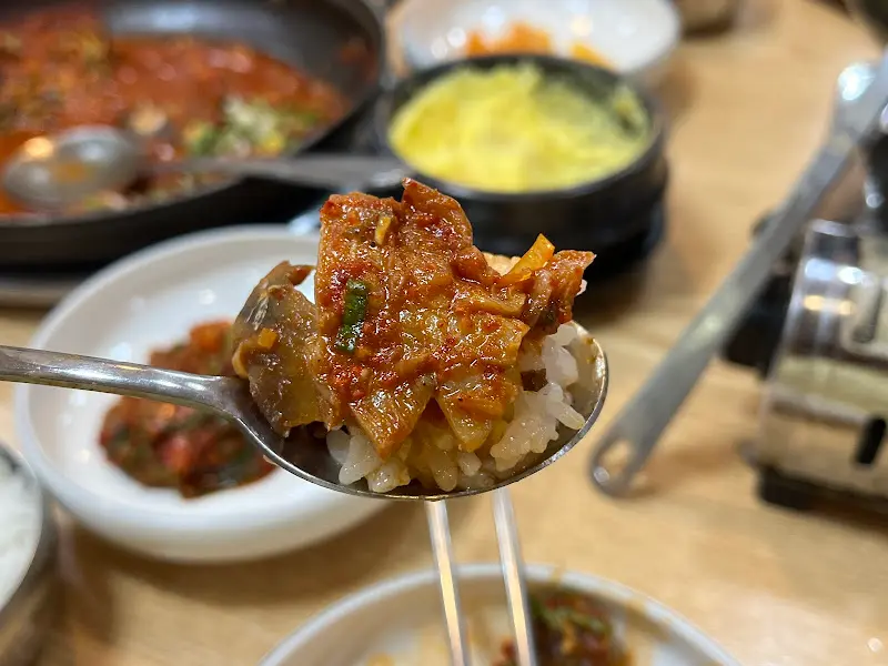 숟가락 위에 닭갈비와 밥을 함께 올려놓은 모습