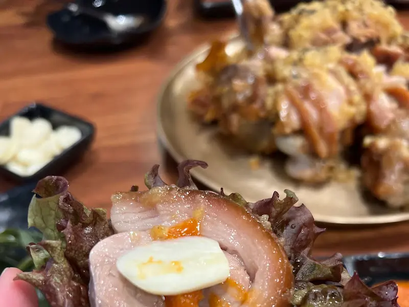 싱싱한 쌈 채소에 족발과 마늘을 올려 쌈 싸 먹는 모습