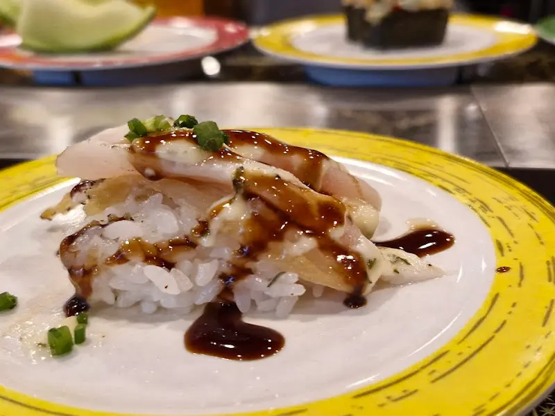 신선한 흰살 생선 위에 소스가 뿌려진 초밥