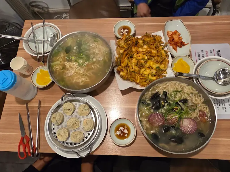 테이블 전체 샷. 해물칼국수, 해물전, 찐만두 등이 놓여있다.