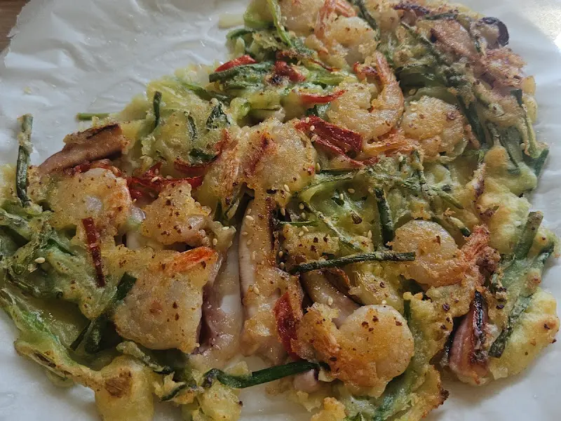 해물파전의 근접 사진, 다양한 해산물과 야채가 조화를 이룬다.