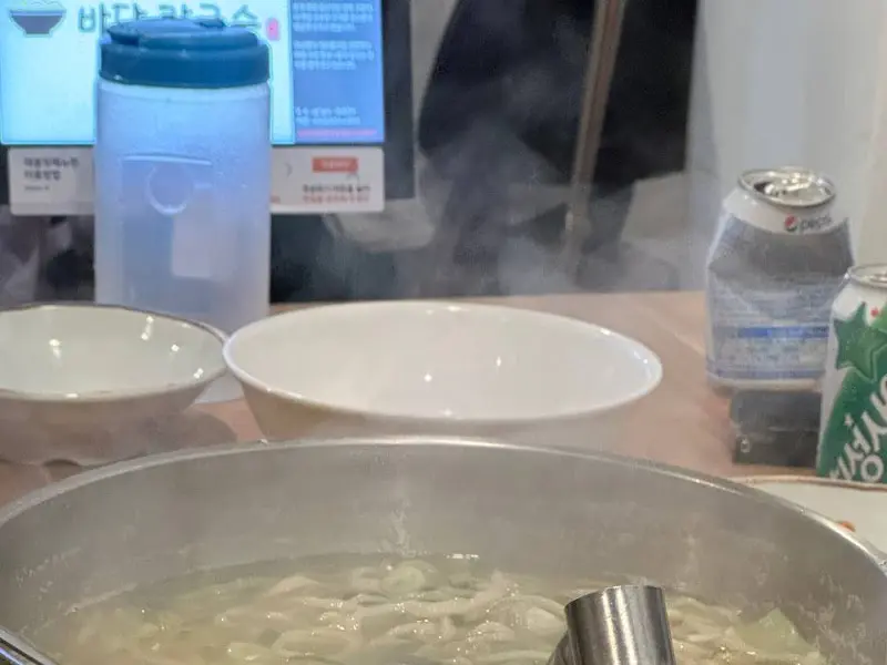 테이블 위에 놓인 칼국수 냄비, 따뜻한 김이 모락모락 피어오른다.
