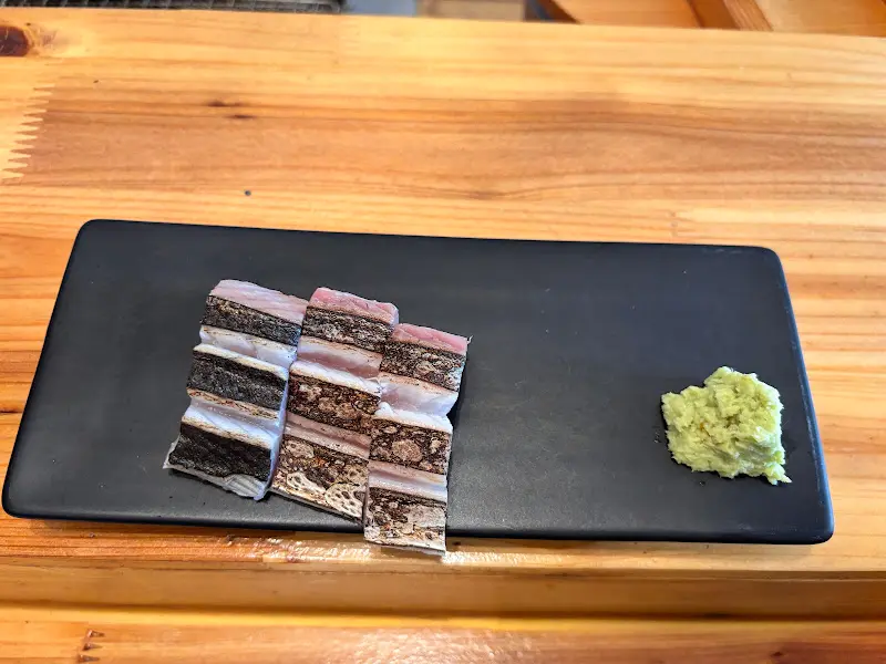 검은색 직사각형 접시에 삼치회와 와사비가 가지런히 놓여 있는 모습