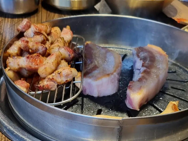 불판 위에서 맛있게 익어가는 삼겹살과 목살