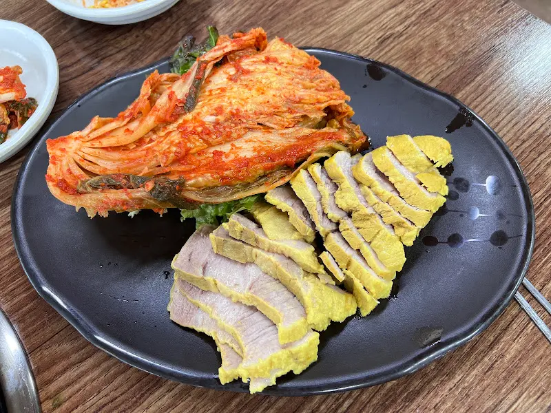 윤기가 자르르 흐르는 수육과 먹음직스러운 김치가 담긴 접시