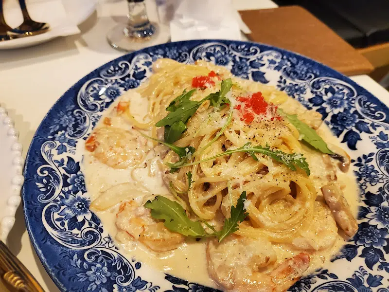 크림 소스에 버무려진 파스타 위에 붉은 색의 명란이 얹혀져 있고, 초록색 채소가 장식되어 있다.