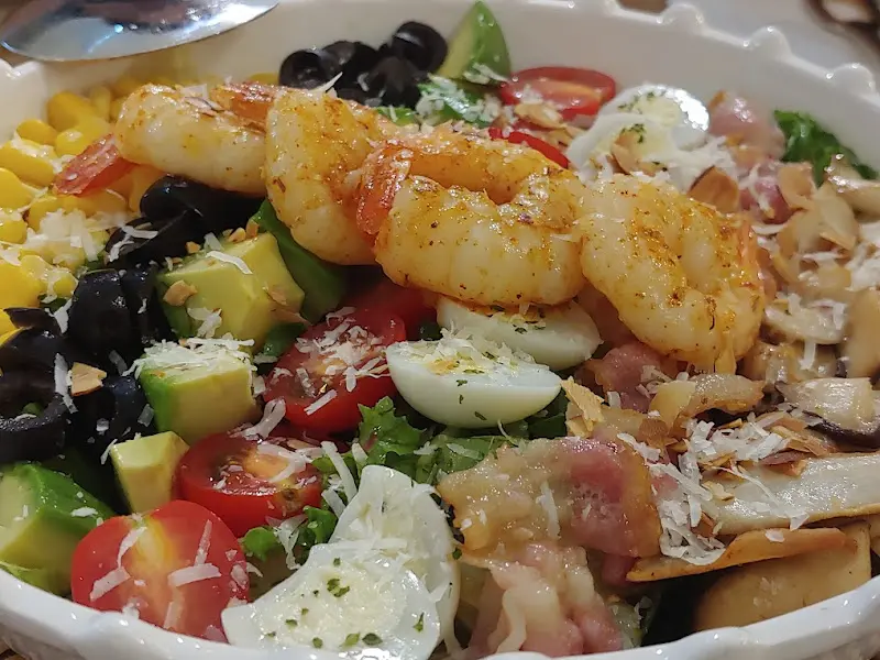 콥 샐러드의 클로즈업 사진. 새우, 아보카도, 토마토 등 다양한 재료들이 신선하게 보인다.