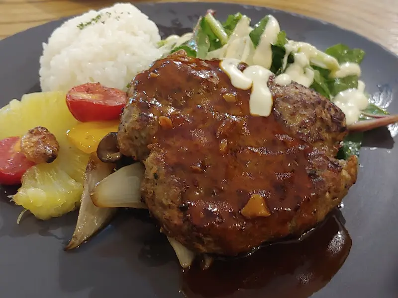 스테이크, 밥, 샐러드, 파인애플이 함께 담겨 있는 플레이트.