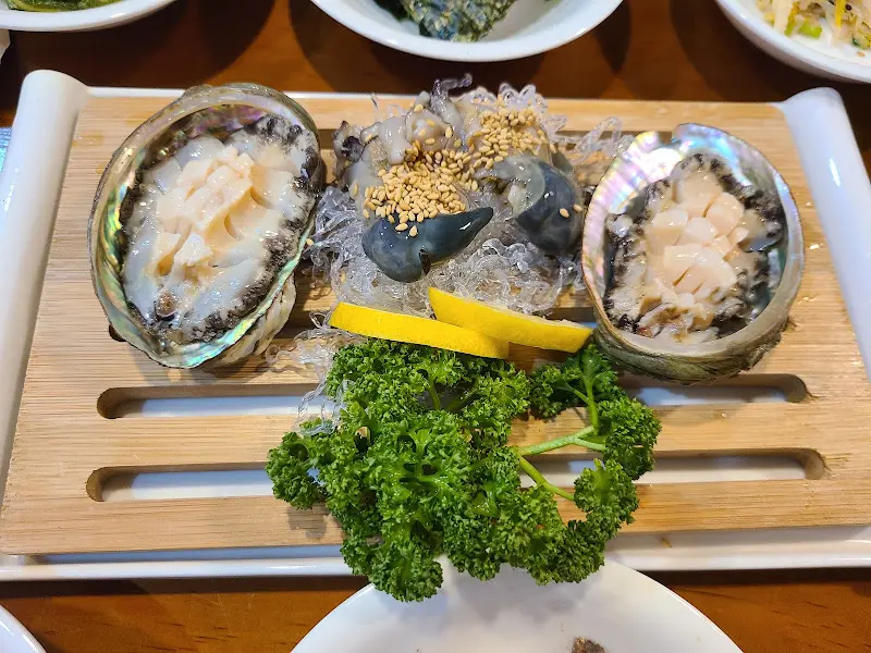 전복회와 해초, 레몬 슬라이스가 함께 담겨 있는 모습