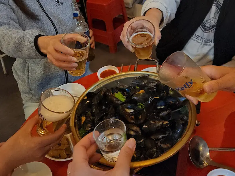 홍합탕과 술잔을 기울이는 사람들