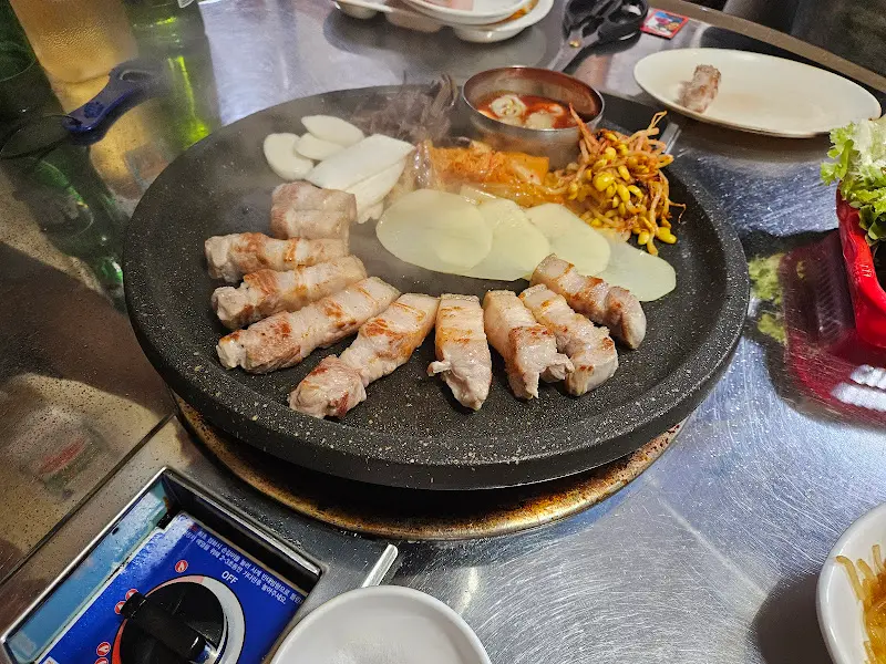 돌판 위에 구워지는 오겹살과 гарнир