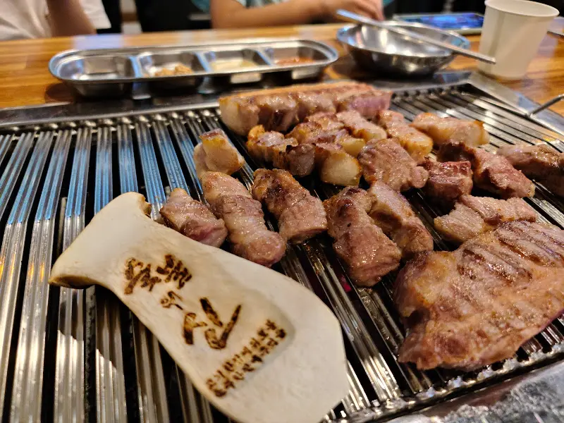 불판 위에서 구워지는 삼겹살과 버섯