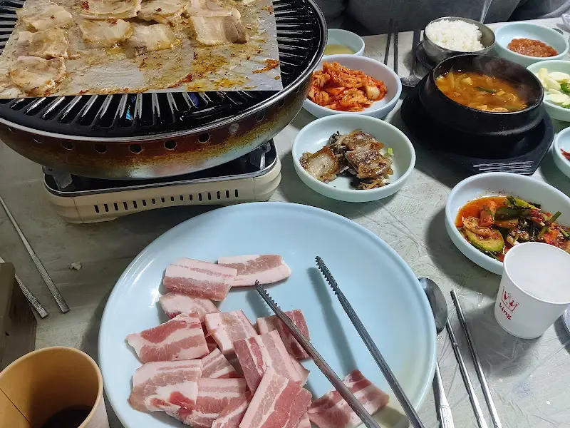냉동 삼겹살과 다양한 반찬이 놓인 테이블