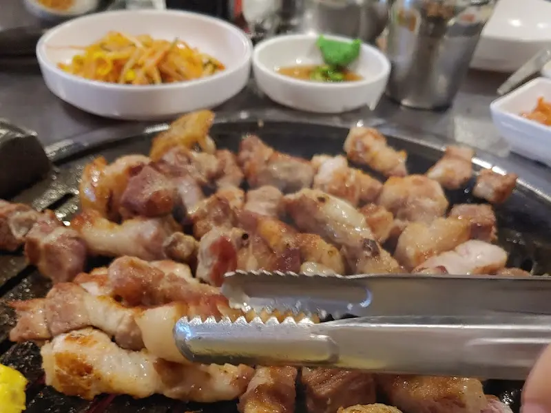 잘 익은 삼겹살을 집게로 들어올리는 모습