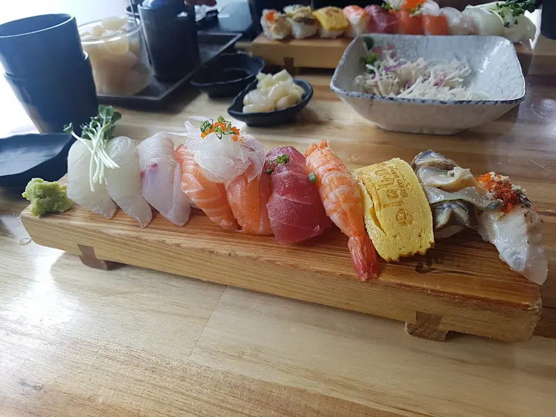 초밥 세트가 담긴 나무 도마와 샐러드, 생강, 락교