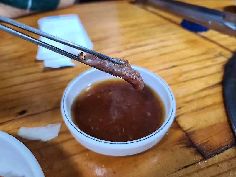 소스를 찍은 오리고기를 젓가락으로 집는 모습