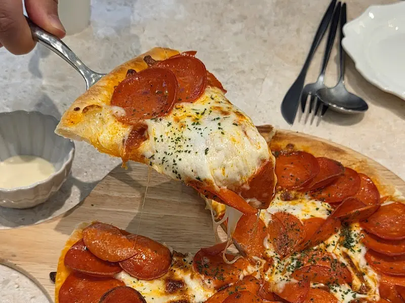 페페로니가 토핑된 피자를 들어올리는 모습