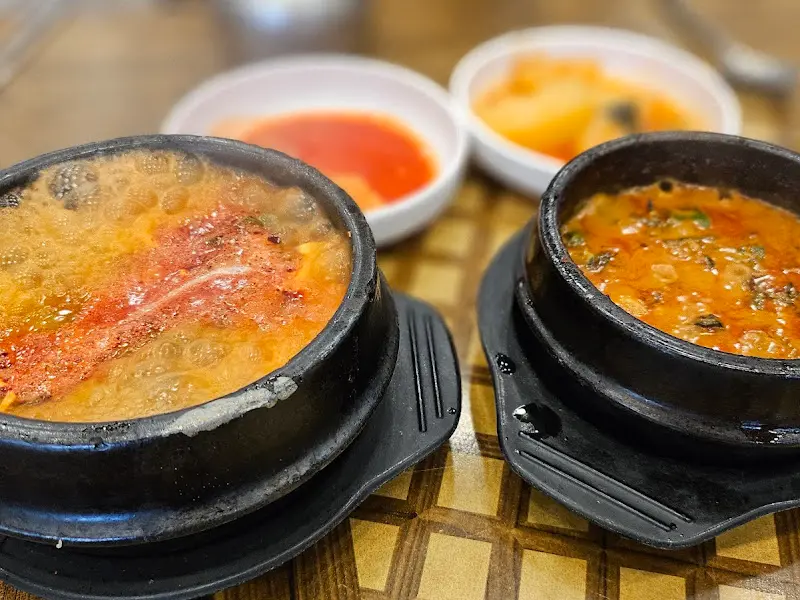 순두부찌개와 우렁쌈장이 뚝배기에 담겨져 테이블에 놓여진 모습