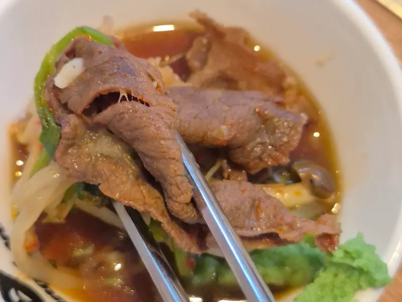 소고기를 젓가락으로 집어 육수에 살짝 데친 모습