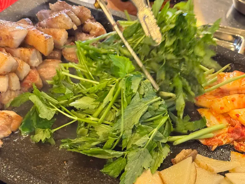 구워진 돼지고기, 김치, 미나리의 조화