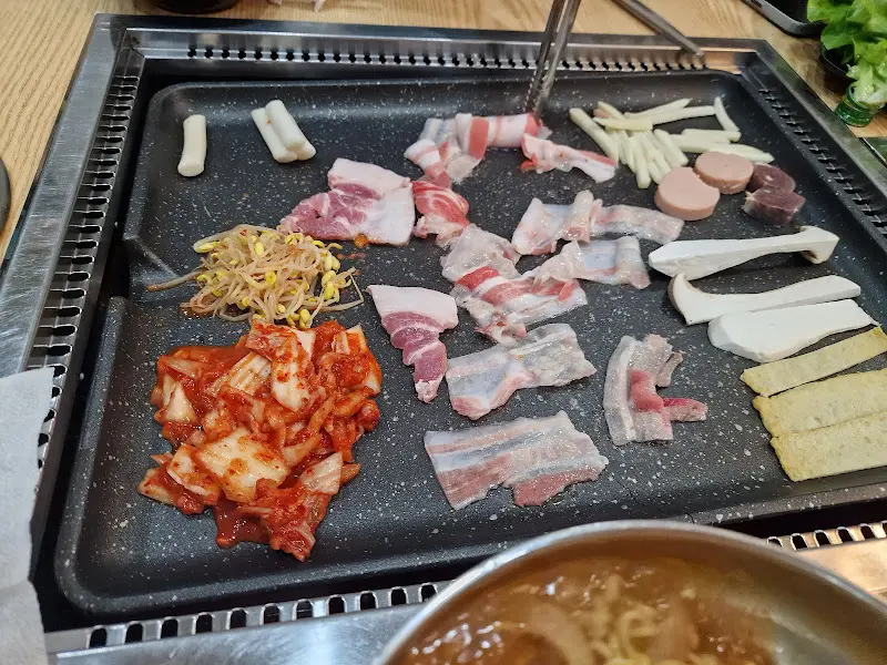 불판 위에 구워지는 김치와 콩나물, 대패 삼겹살