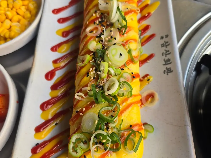 케첩과 머스타드, 파와 깨로 장식된 계란말이의 클로즈업 샷