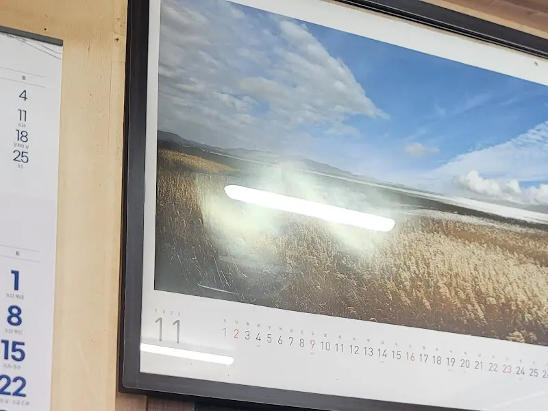 달력과 풍경 사진 액자가 걸린 식당 내부