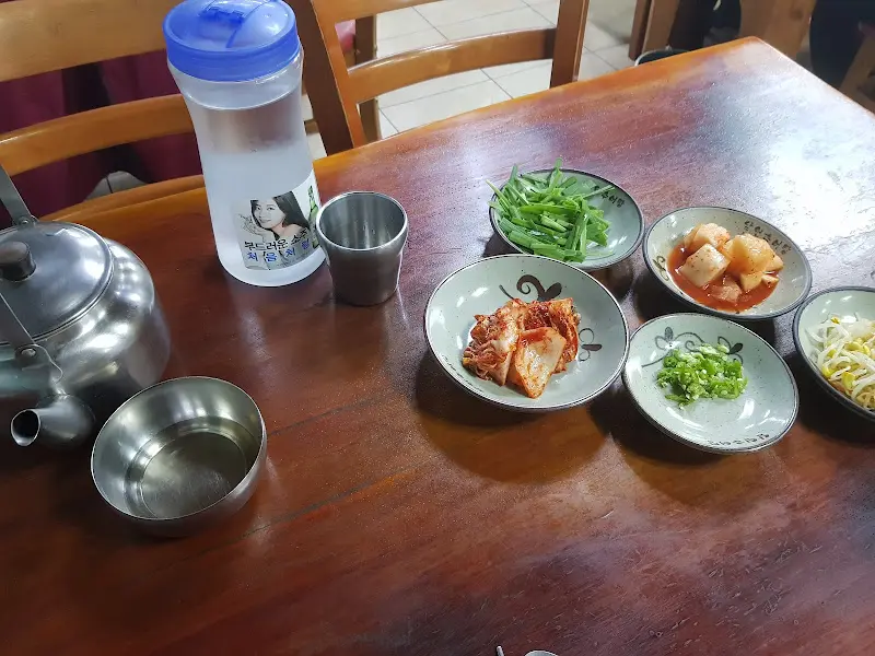 테이블 위에 놓인 주전자와 컵, 그리고 정갈하게 담긴 반찬들