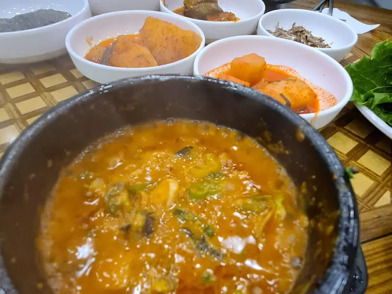 우렁쌈장이 담긴 뚝배기와 다양한 밑반찬들