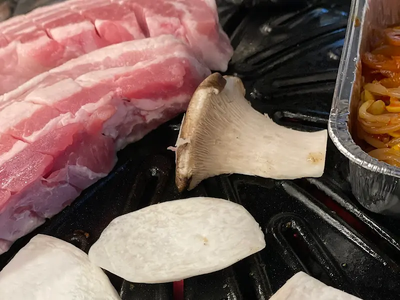 불판 위에 올려진 삼겹살과 버섯