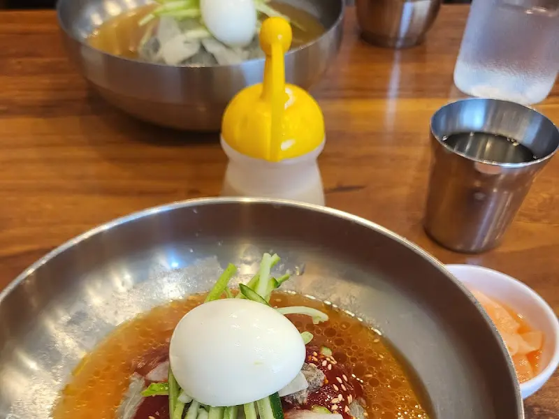 테이블 위에 놓인 함흥냉면 그릇과 겨자 소스