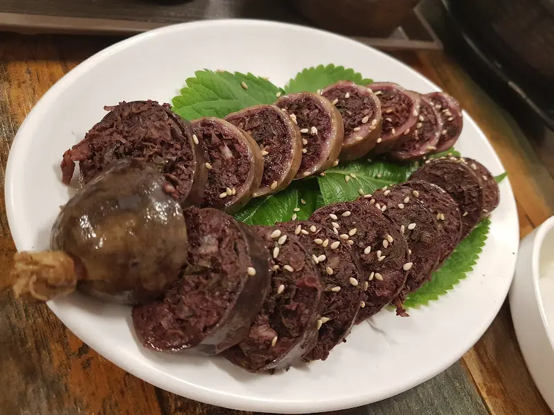 윤기가 흐르는 피순대 한 접시, 참깨가 듬뿍 뿌려져 있다.