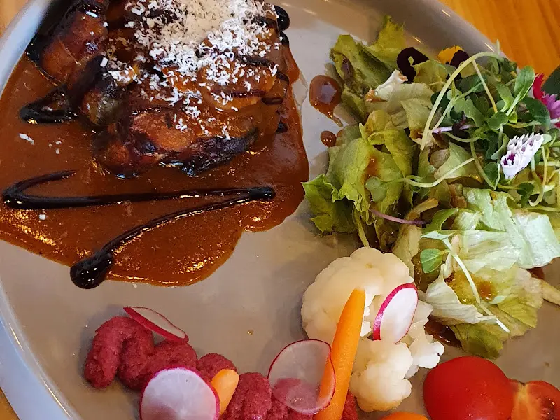 테이블 위에 놓인 접시에는 갈비찜과 샐러드가 함께 담겨 있다. 갈비찜 위에는 하얀 치즈가 뿌려져 있고, 샐러드에는 꽃잎이 장식되어 있다.